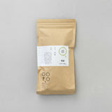 A packaged bag of Tomizawa Tea Garden's Kumamoto Shira-ore Leaf Stem Tea with a label indicating it's a naturally grown green tea product.